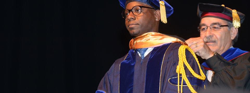 Associate dean Carlos V. Grijalva performs the hooding ceremony for a doctoral graduate